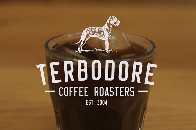 Terbodore Coffeee Roasters lofo with cold coffee in background