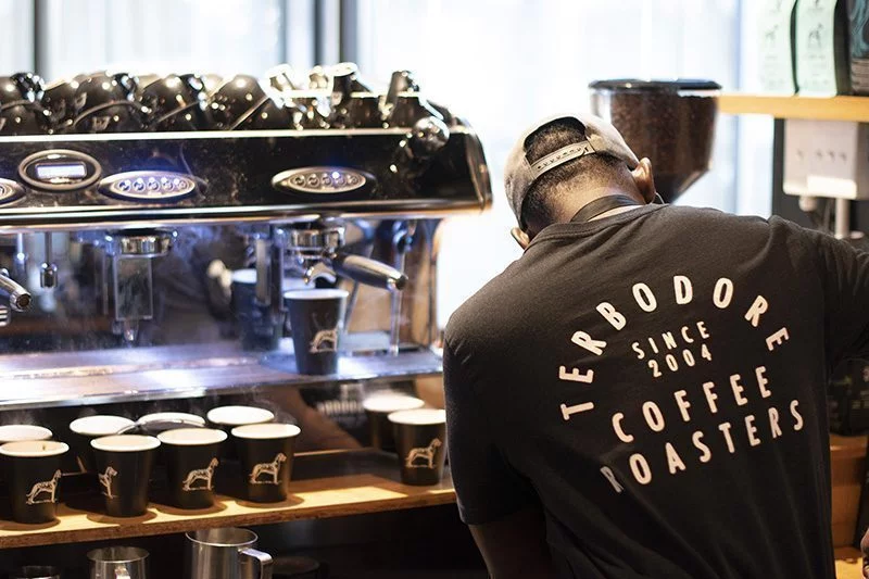 Man making coffee inside Terbodore Family Restaurant wearing Terbodore Coffee roaster tshirt