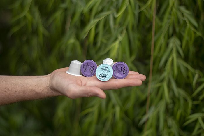 Man holding Terbodore Compostable Capsules with greenery in the background