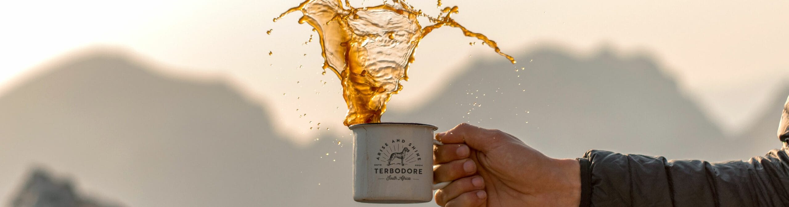 an holding a Terbodore coffee mug with Great Dane dog on it, spilling coffee